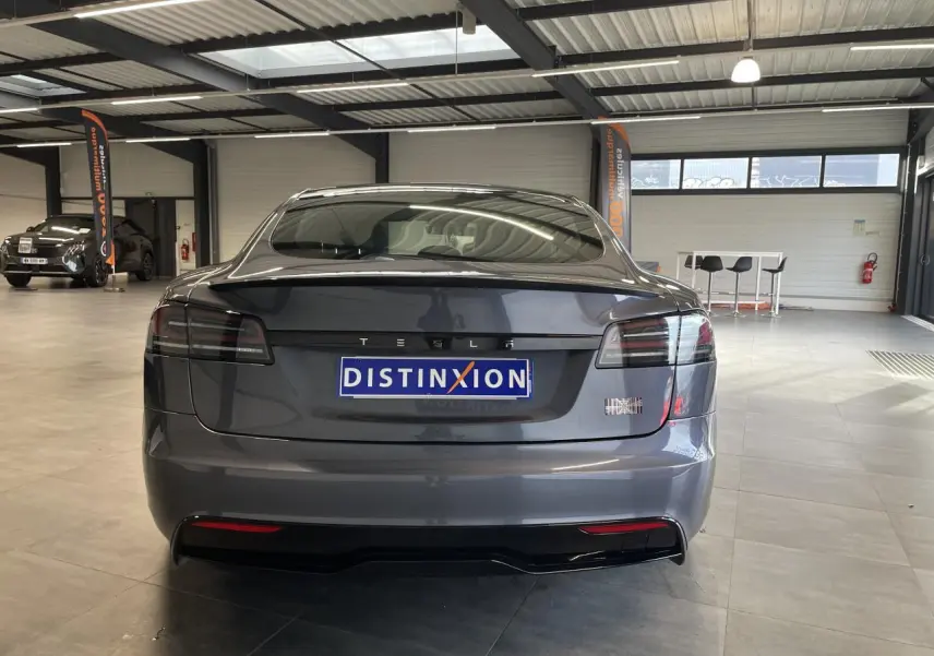 Vue arrière d'une Tesla Model S Plaid gris foncé dans un showroom avec feux arrière LED fumés.