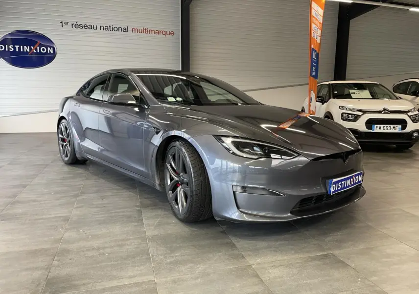 Tesla Model S Plaid gris foncé vue 3/4 avant en intérieur avec jantes sport et calandre lisse.