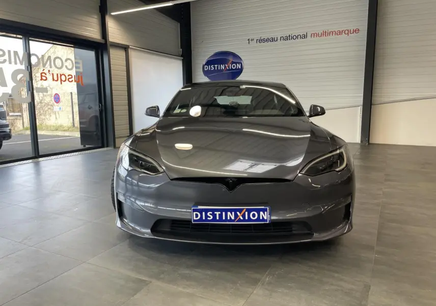 Tesla Model S Plaid gris foncé vue de face dans un showroom avec reflets sur la carrosserie lisse.
