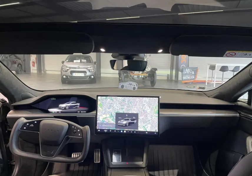 Vue intérieure avant du Tesla Model S Plaid 2023 gris foncé, avec grand écran tactile central et volant yoke.