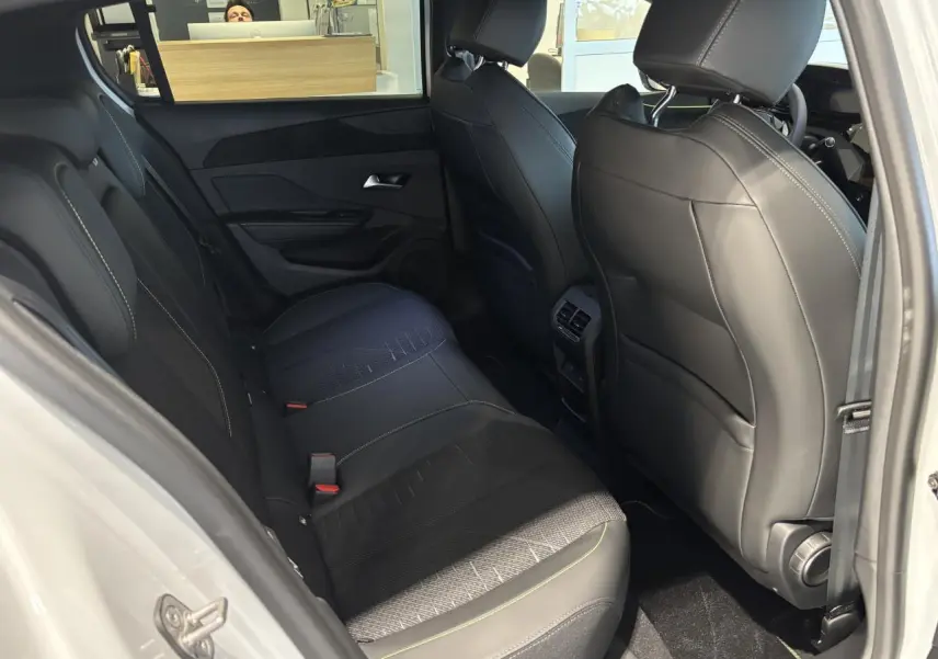 Vue intérieure arrière côté droit de la Peugeot 308 blanche avec sellerie noire et surpiqûres vert Adamite.