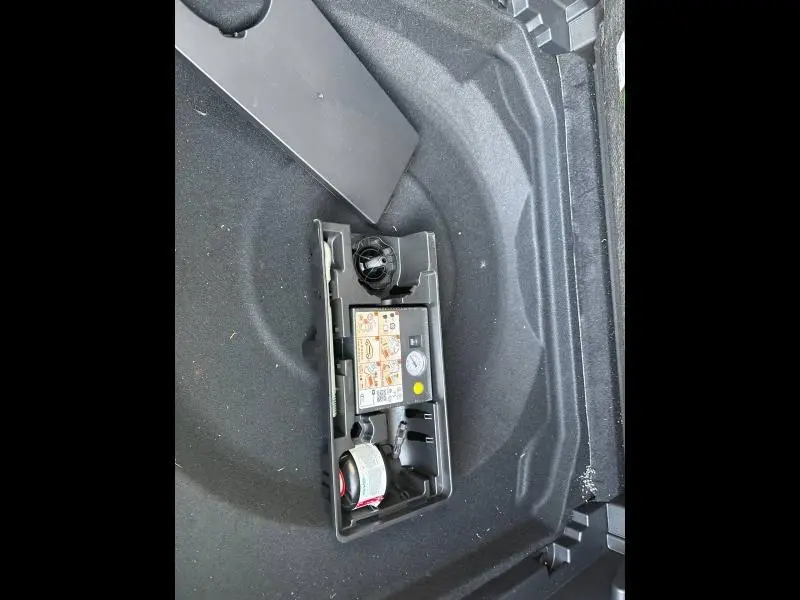 Vue en plongée sur le coffre du Citroën C5 Aircross gris Platinium, montrant le compresseur et kit de réparation pneus.