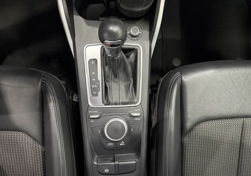 Vue plongeante sur la console centrale noire de l'Audi Q2 2.0 TDI 190 S-Line avec levier de vitesses automatique et sièges en cuir partiel.