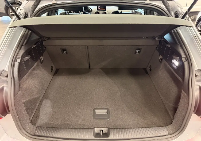 Coffre ouvert vu de l'arrière d'un Audi Q2 gris 2017, montrant un espace de chargement propre et bien éclairé.