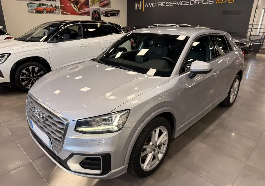 Audi Q2 gris vue 3/4 avant droit en intérieur, mettant en valeur sa calandre et ses phares LED distinctifs.