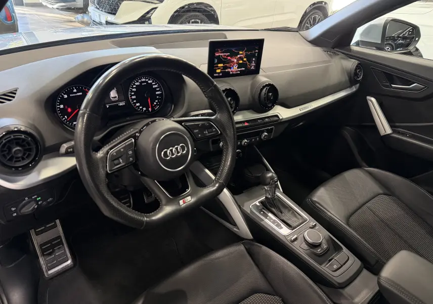 Vue intérieure côté conducteur de l'Audi Q2 2.0 TDI 190 S-Line 2017, avec tableau de bord noir et écran central GPS.