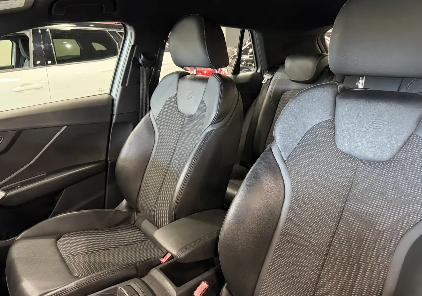 Vue intérieure des sièges avant en cuir noir avec logo S-Line embossé sur un Audi Q2 gris, version 2017.