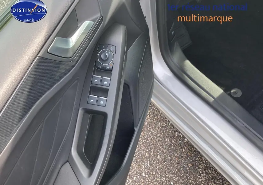 Gros plan sur la portière côté conducteur gris avec commandes électriques et haut-parleur intégré.