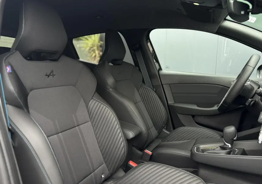Intérieur de la Renault Clio Esprit Alpine 2025, vue côté gauche sur sièges sport noirs avec surpiqûres bleues.