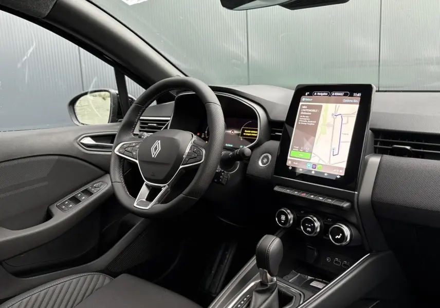 Intérieur avant Renault Clio 2025 noir, volant multifonction, écran tactile vertical et console centrale avec boîte auto.
