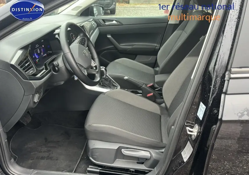 Vue intérieure côté conducteur de la Volkswagen Polo 2025 noir intense nacré, avec sièges tissu gris et tableau de bord moderne.