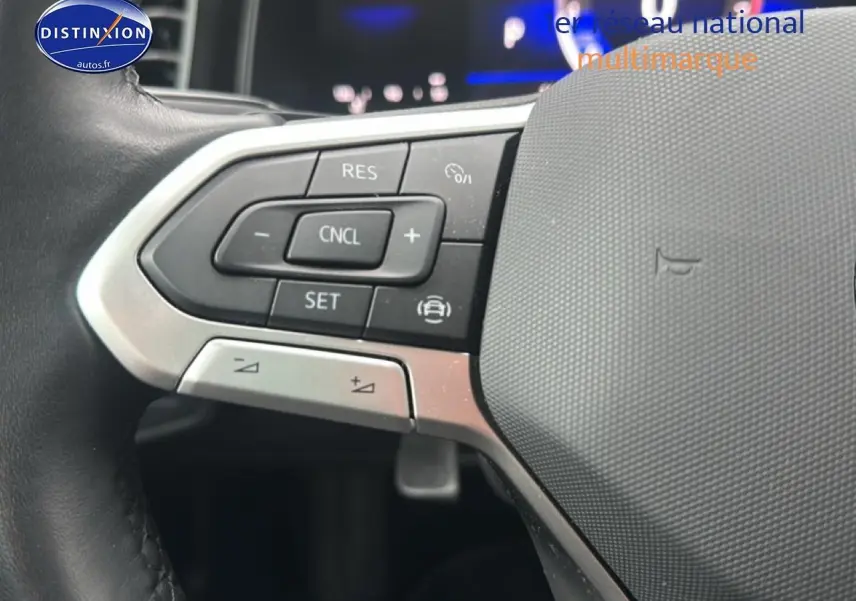 Gros plan sur les commandes au volant en cuir de la Volkswagen Polo noire, avec boutons de régulateur de vitesse.