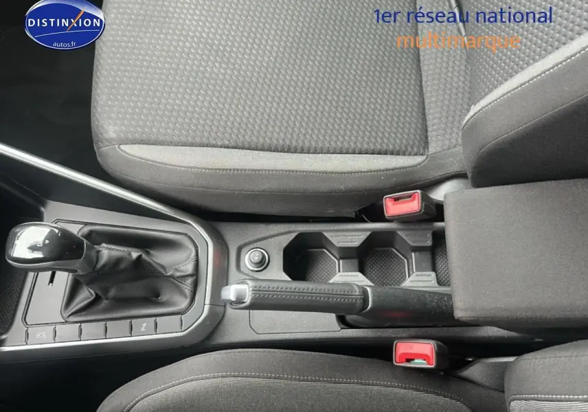 Vue plongeante sur la console centrale noire avec levier de vitesses automatique et accoudoir entre les sièges tissu noir.