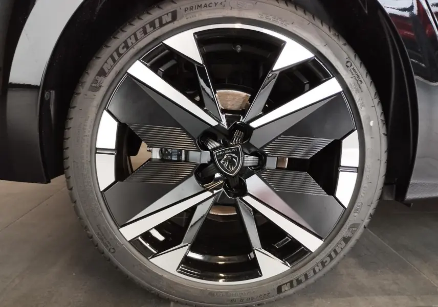 Gros plan sur la jante alliage 18 pouces bi-tons noir et argent avec logo Peugeot au centre sur Peugeot 308 noir métallisé.