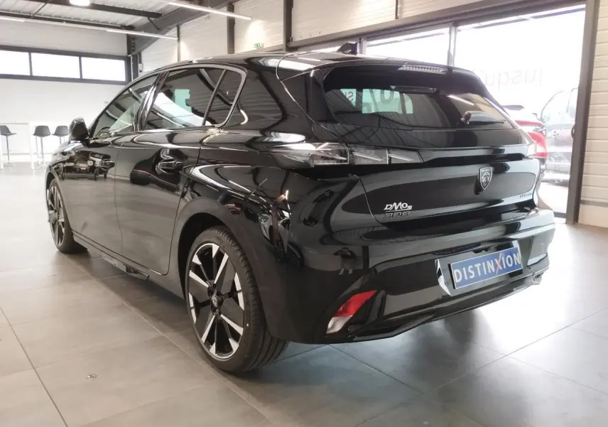 Vue 3/4 arrière droite d'une Peugeot 308 noire métallisée avec jantes alliage bi-tons et feux arrière LED griffés.