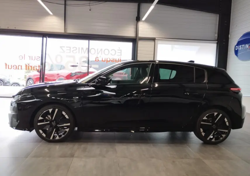 Profil droit d'une Peugeot 308 noire métallisée avec jantes alliage bi-tons et détails noirs brillants en intérieur showroom.