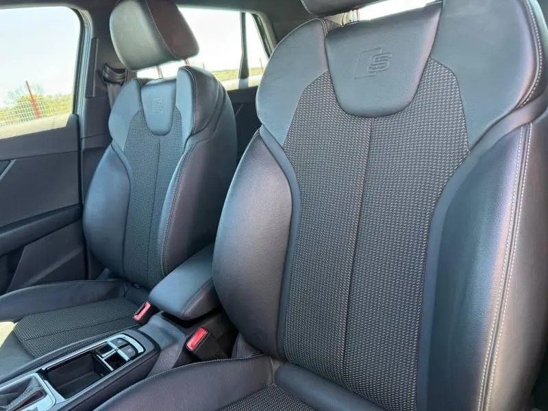 Gros plan sur les sièges avant en cuir noir avec logo S embossé, intérieur de l'Audi Q2 35 TDI S line 2025.
