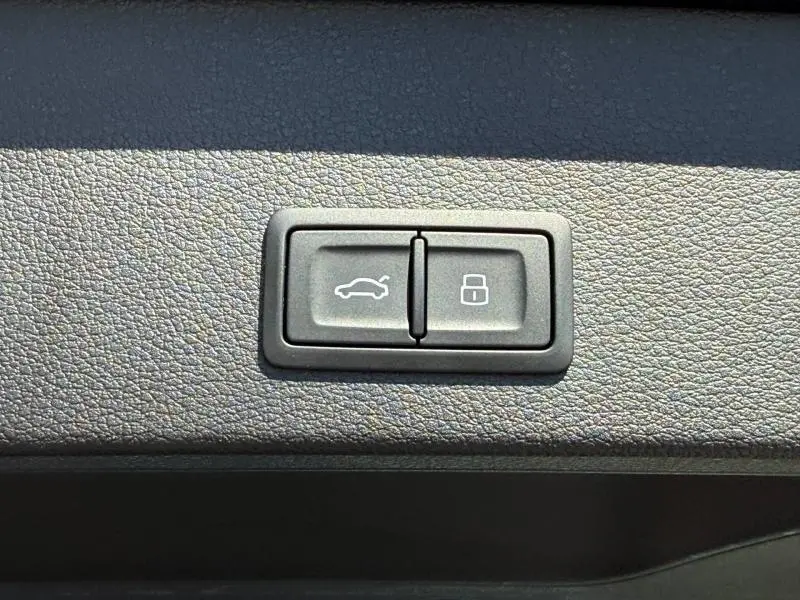 Boutons de commande pour ouverture du coffre et verrouillage, sur panneau intérieur noir texturé d'Audi Q2 35 TDI S line 2025.