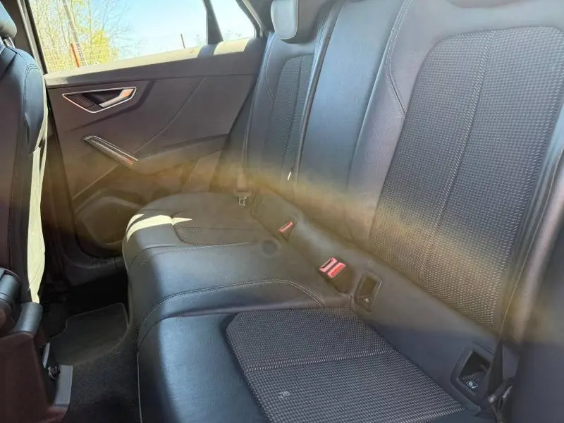 Vue intérieure montrant la banquette arrière en cuir noir de l'Audi Q2 35 TDI S line 2025, avec lumière naturelle.