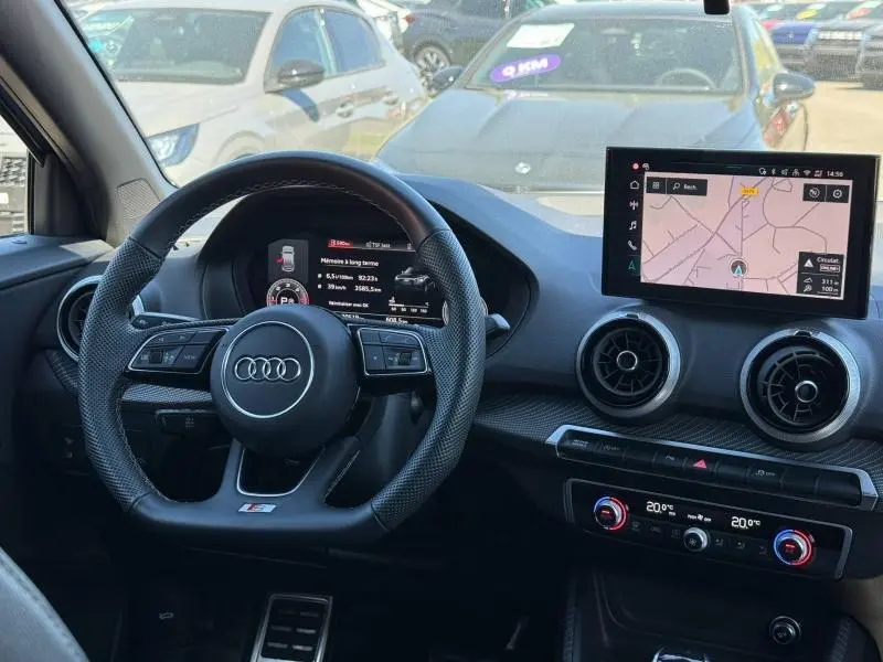 Vue intérieure de l'Audi Q2 35 TDI S line 2025 montrant le volant sport, l'écran central tactile et les aérateurs ronds.