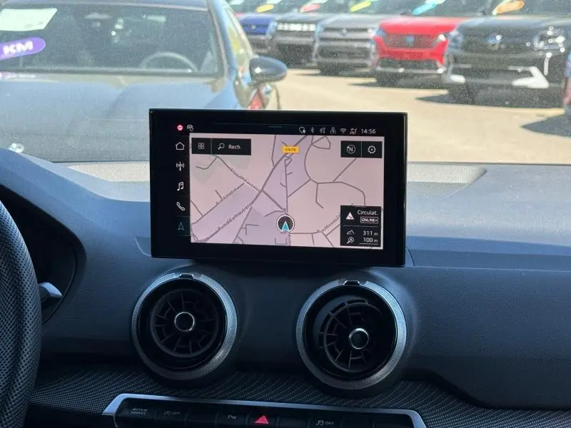 Vue intérieure du tableau de bord de l'Audi Q2 2025 avec écran tactile central et aérateurs ronds noirs.
