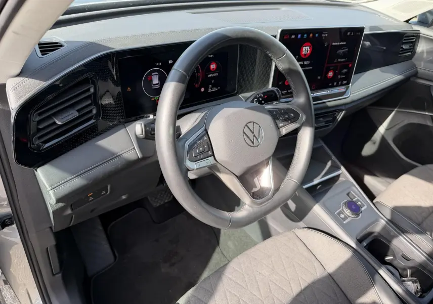Vue intérieure côté conducteur du Volkswagen Tiguan gris 2025, volant cuir multifonction et tableau de bord digital.