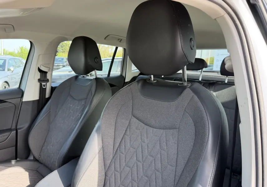 Vue intérieure rapprochée des sièges avant gris tissu et cuir du Volkswagen Tiguan 2025, côté droit ouvert.