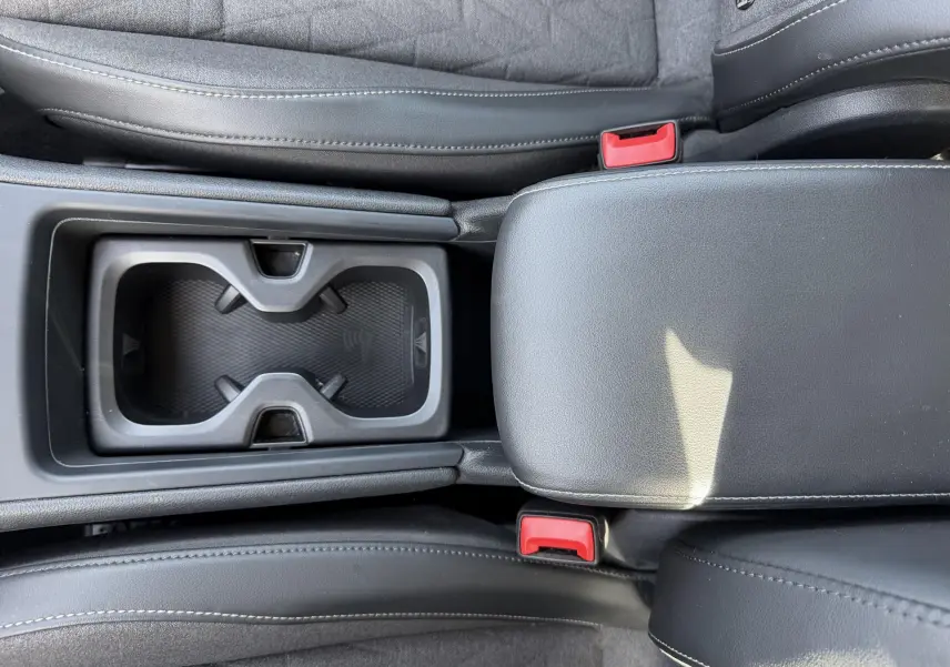 Vue plongeante sur la console centrale noire avec porte-gobelets et accoudoir cuir du Volkswagen Tiguan 2025.