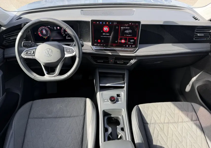 Vue intérieure avant du Volkswagen Tiguan gris 2025, tableau de bord moderne avec écran tactile et volant multifonction cuir.