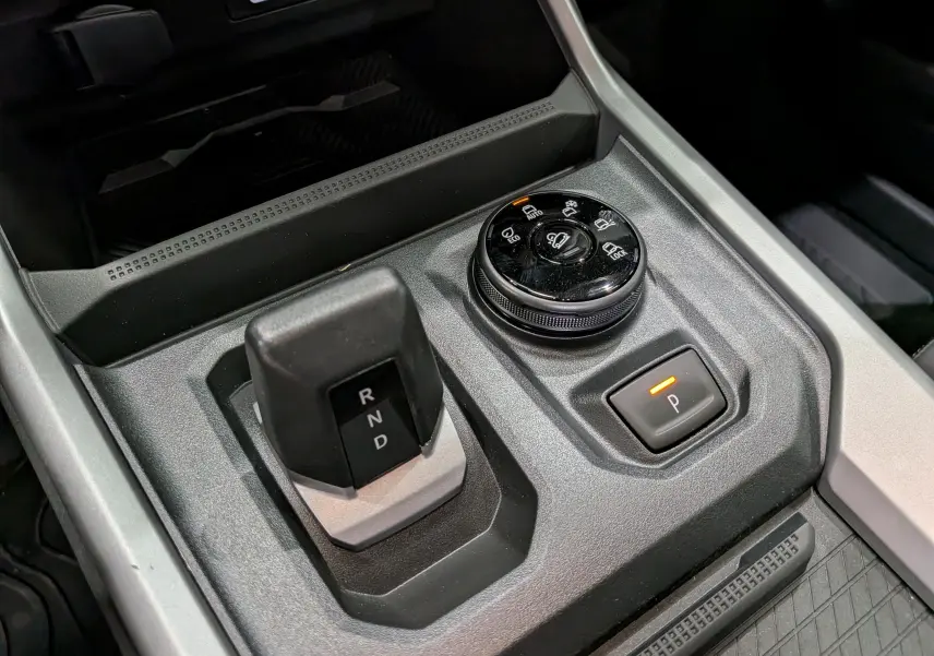 Gros plan sur la console centrale du Dacia Bigster Hybrid-G 150 4x4 avec sélecteur de boîte auto et commande de modes de conduite.