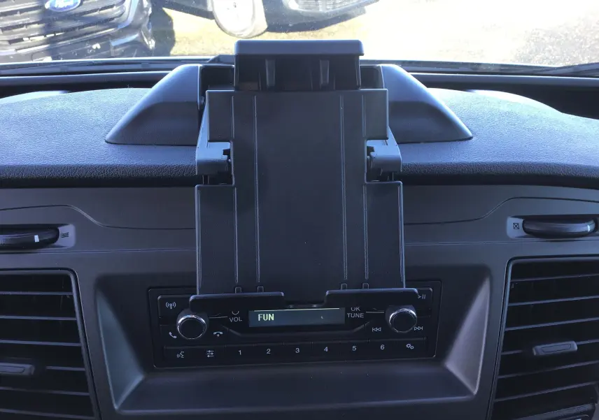 Vue rapprochée du tableau de bord noir du Ford Transit Châssis Cabine blanc 2024, avec support tablette et radio intégrée.