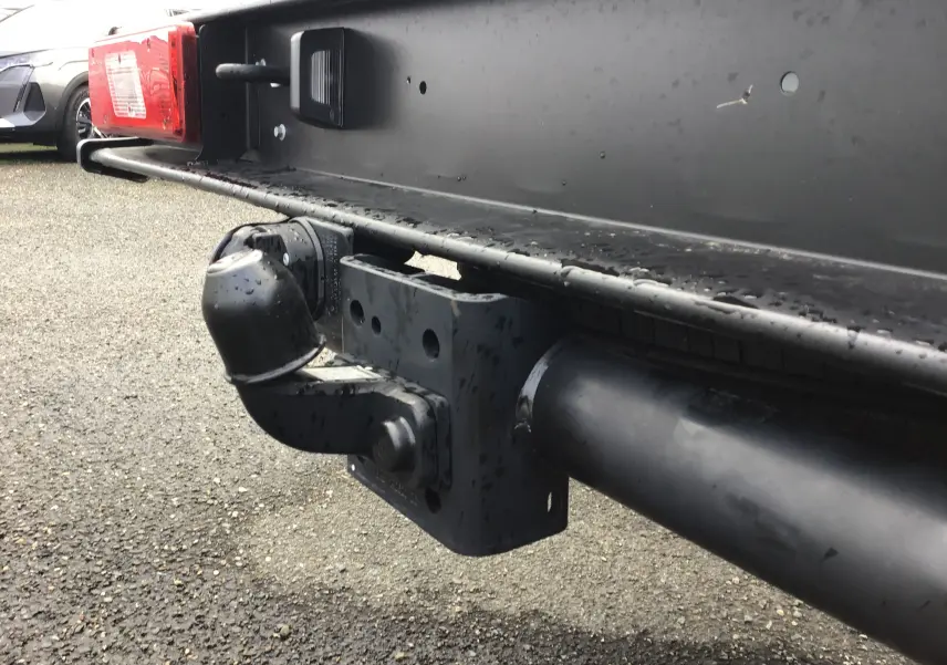 Gros plan sur l'attelage arrière noir d'un Ford Transit Chassis Cabine blanc, avec feu rouge et plaque de fixation visible.