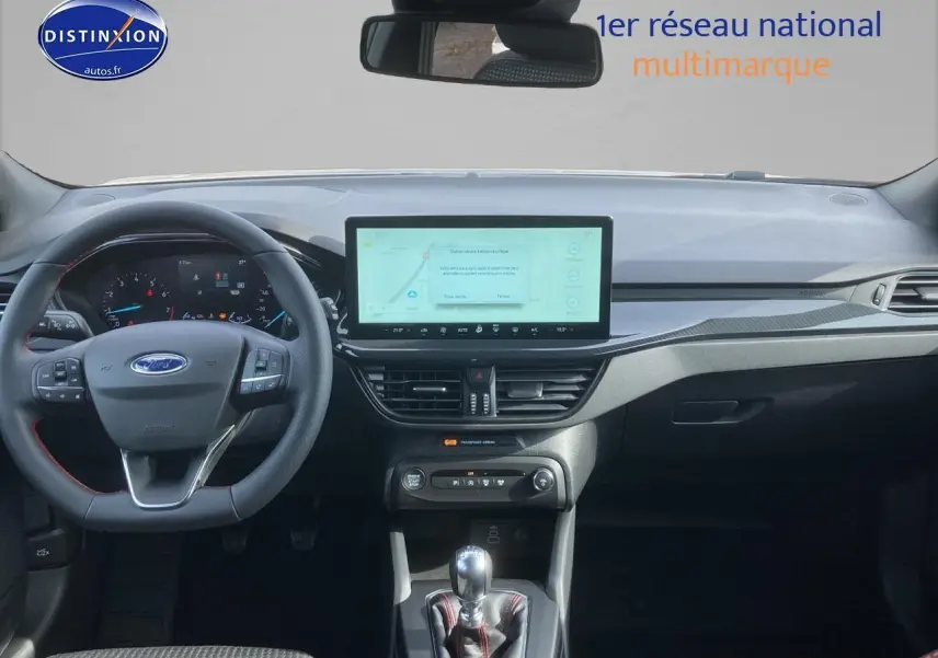 Intérieur Ford Focus 2025 vue tableau de bord avec écran tactile 13,2'', volant cuir noir à coutures rouges et levier manuel.