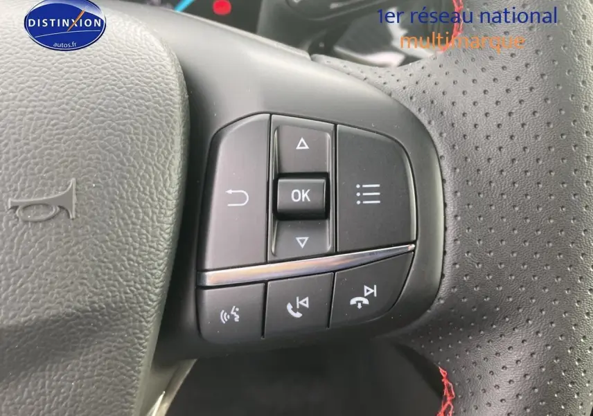 Gros plan sur les commandes à gauche du volant perforé noir avec coutures rouges d'une Ford Focus gris 2025 finition ST-Line X.