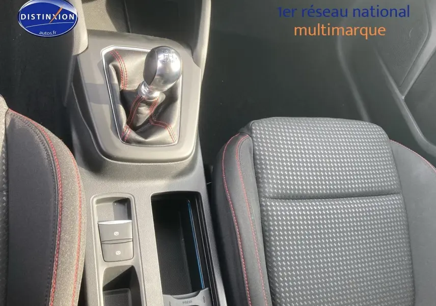 Gros plan sur la console centrale et le levier de vitesse manuel avec coutures rouges, siège avant tissu gris à surpiqûres rouges.