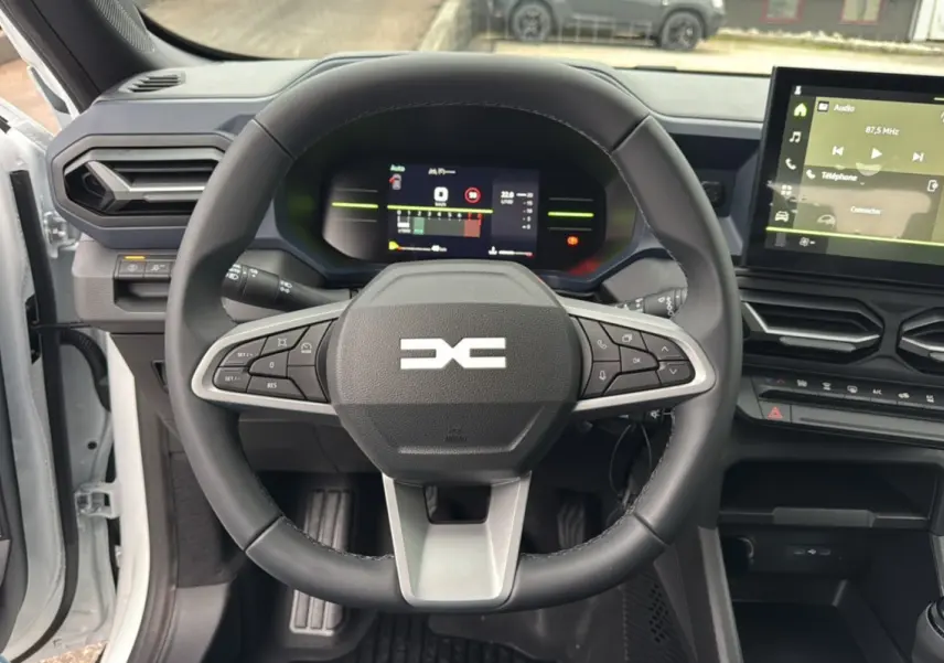 Vue intérieure centrée sur le volant multifonction du Dacia Duster 2025 avec tableau de bord numérique et écran tactile.
