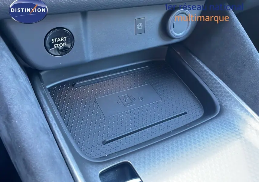 Gros plan sur la console centrale du Nissan Qashqai 2025 avec zone de recharge sans fil et bouton start/stop.