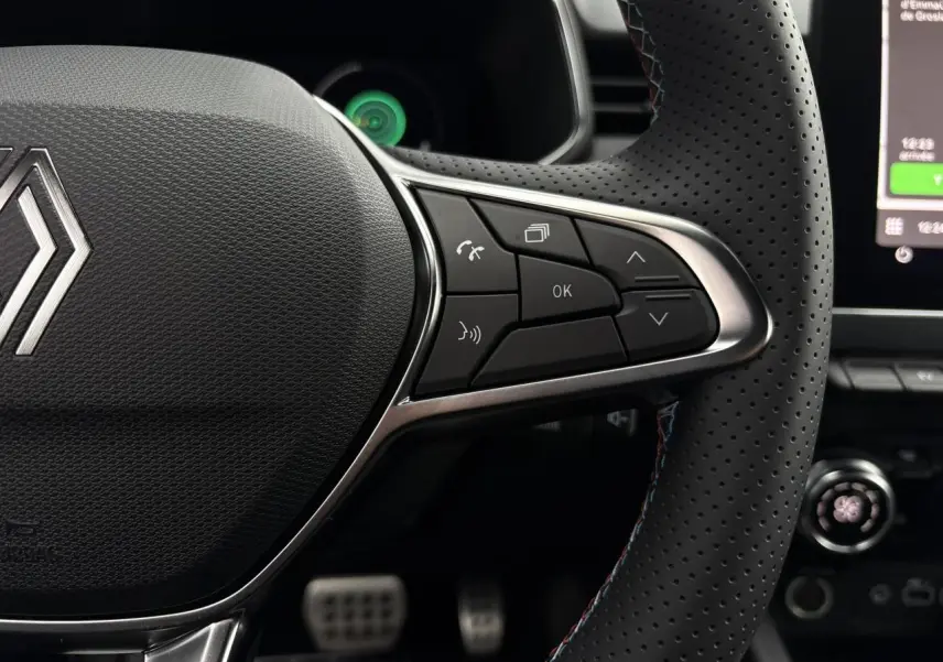 Gros plan sur le volant multifonction perforé avec surpiqûres bleues de la Renault Clio Gris Rafale 2025, version Esprit Alpine.