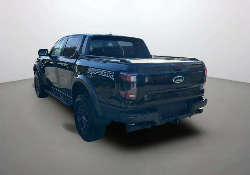 Vue 3/4 arrière gauche du Ford Ranger Raptor noir absolu avec logo Raptor sur la benne et jantes noires.