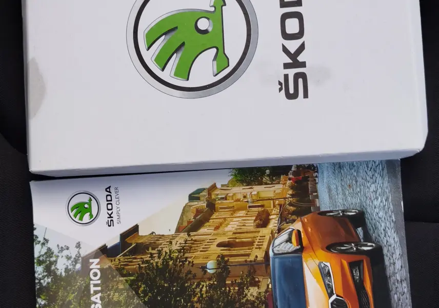 Vue avant 3/4 droit d'une ŠKODA Fabia orange garée en ville avec calandre noire et phares LED allumés.