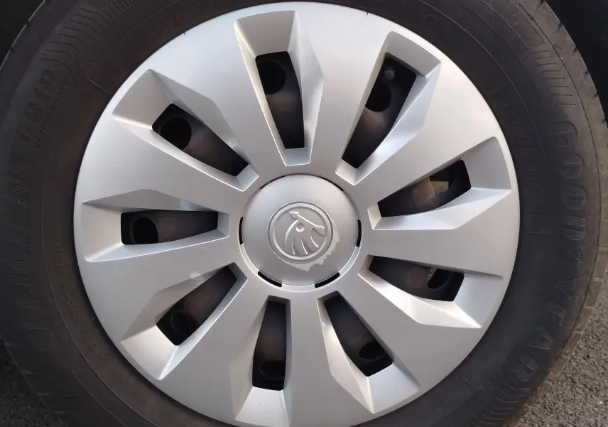 Gros plan sur la roue avant droite d’une Skoda Fabia blanche, avec enjoliveur argenté au design moderne et logo central.