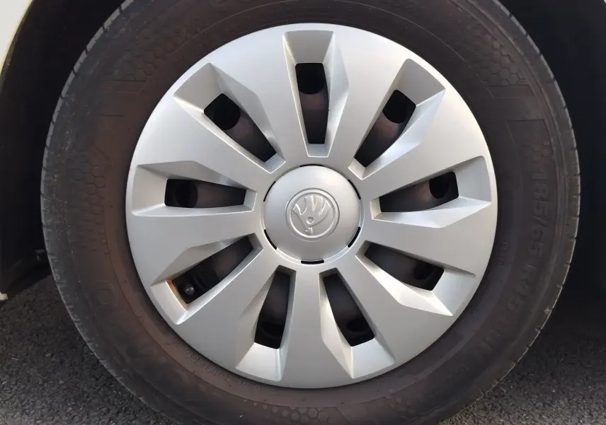 Gros plan sur la roue avant gauche de la Skoda Fabia blanc lune 2022 avec enjoliveur argenté et logo central.