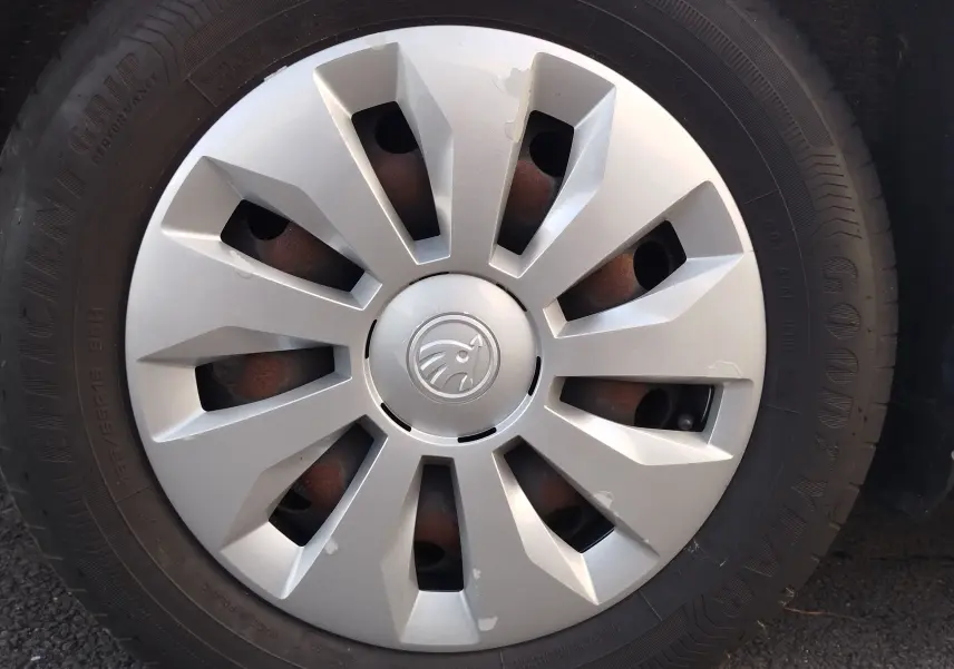 Gros plan sur la roue avant droite d'une Skoda Fabia blanc lune, avec enjoliveur argenté et logo central visible.