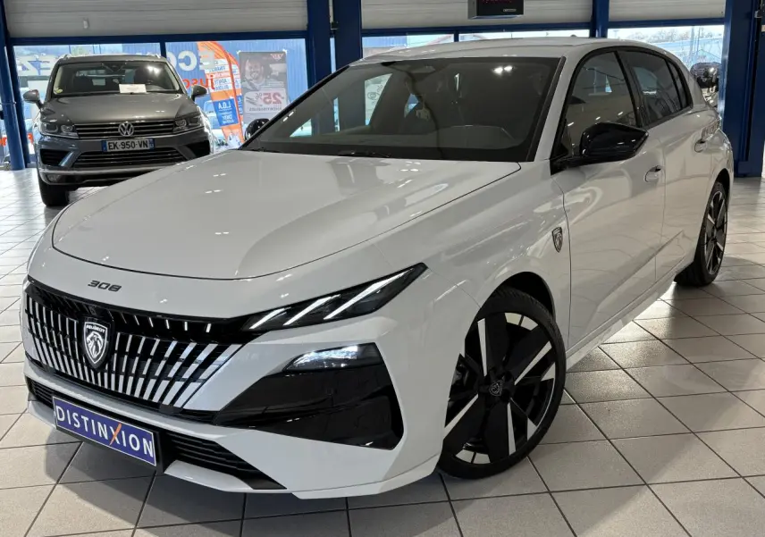 Vue 3/4 avant droite d'une Peugeot 308 blanche avec calandre noire à liserés chromés et jantes alliage bi-ton.