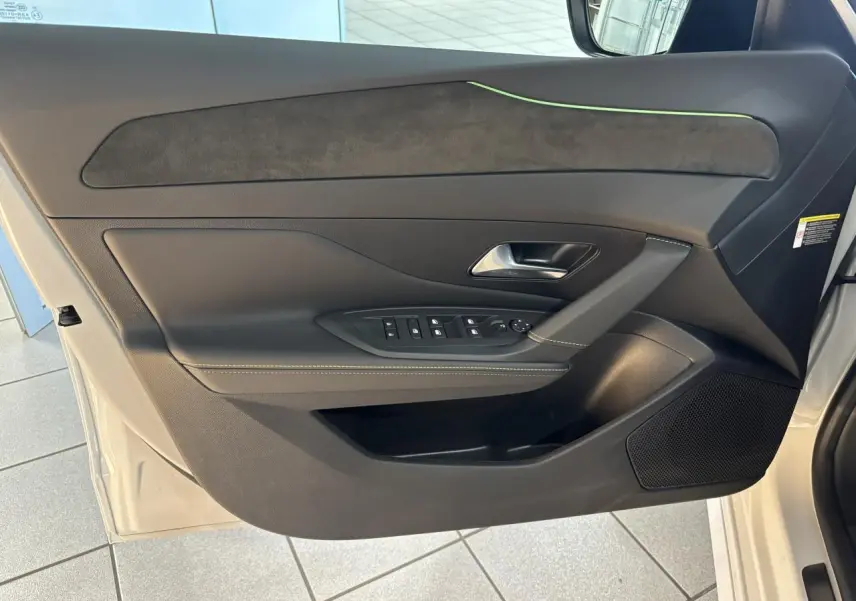 Vue intérieure de la porte avant gauche blanche du Peugeot 308 Hybrid avec surpiqûres vert Adamite et insert Alcantara.