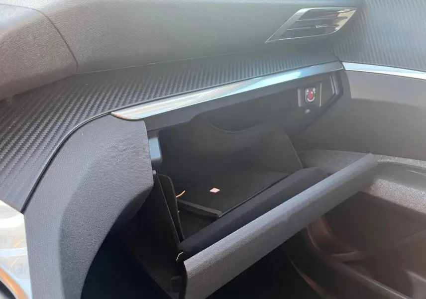 Gros plan sur la boîte à gants ouverte côté passager du Peugeot 3008 2023, intérieur noir avec finition carbone.