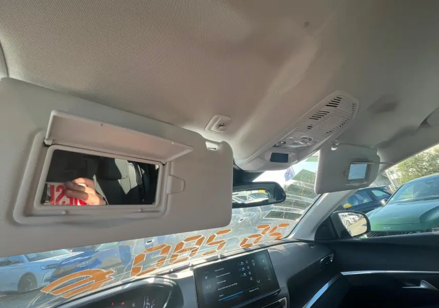Vue intérieure du tableau de bord et pare-soleil ouvert côté conducteur d'un Peugeot 3008 gris avec écran tactile allumé.