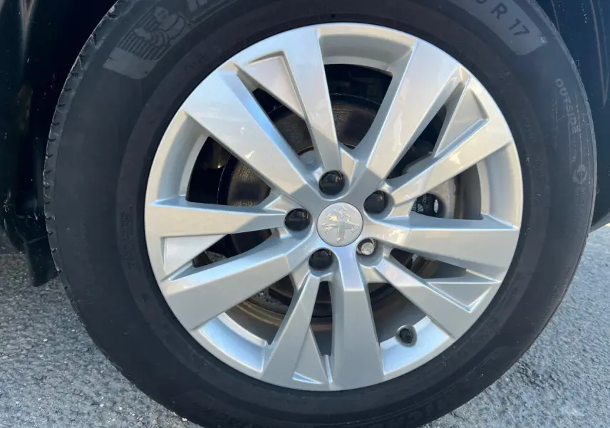 Gros plan sur la jante alliage 17 pouces argentée du Peugeot 3008 gris Artense, avec logo lion au centre.