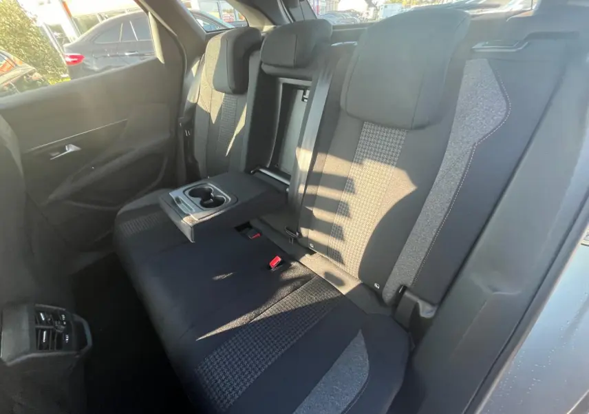 Vue intérieure arrière droite des sièges tissu gris et noir avec accoudoir central déployé du Peugeot 3008 2023 gris Artense.