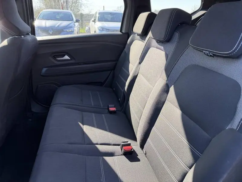 Vue intérieure sur la banquette arrière du Dacia Jogger 2025, sièges tissu gris avec appuie-têtes et ceintures visibles.
